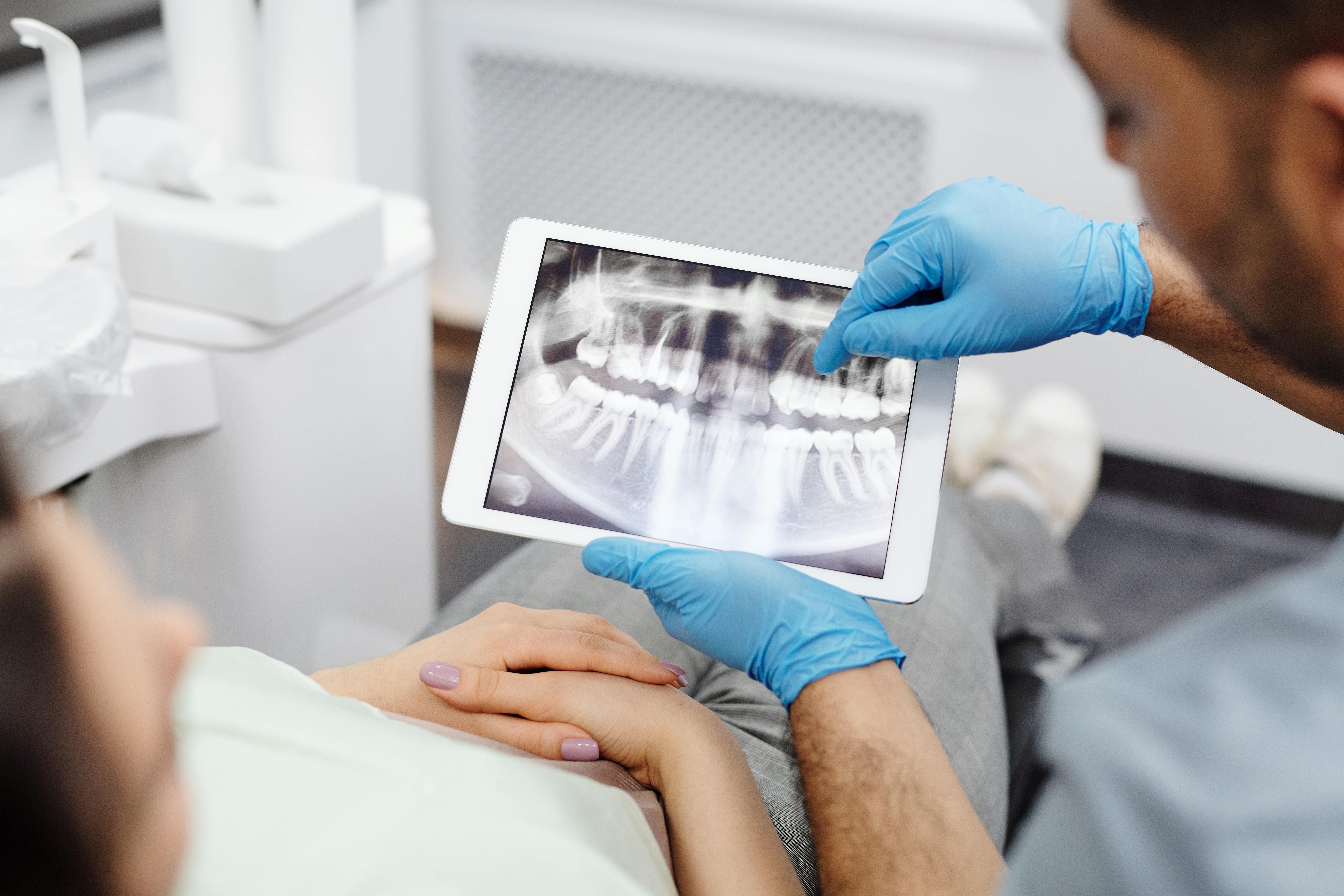 dentist shows patient's dental x-rays and problems on tablet