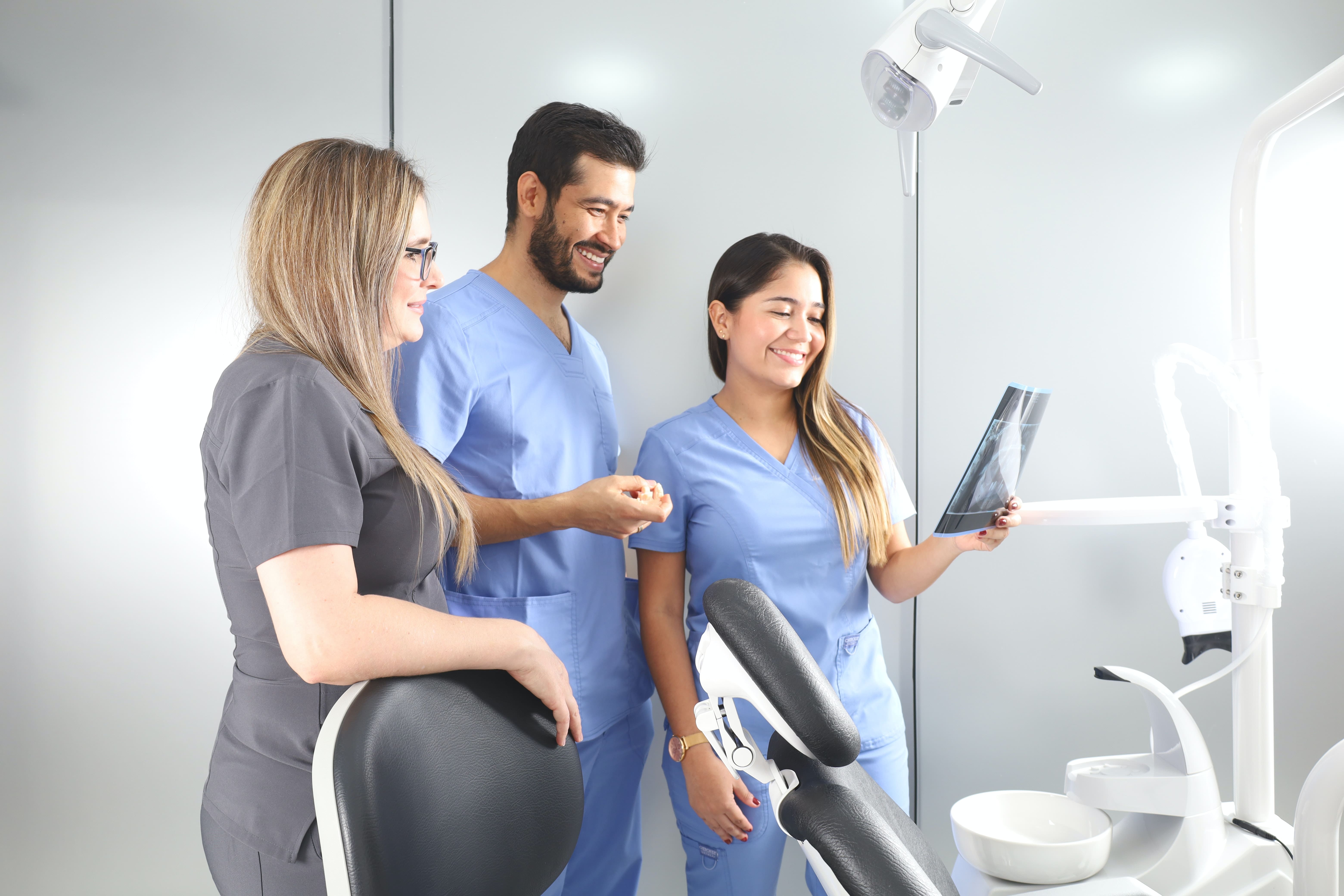 two women and a man look at diagnostic results with artificial intelligence imaging in a dental clinic