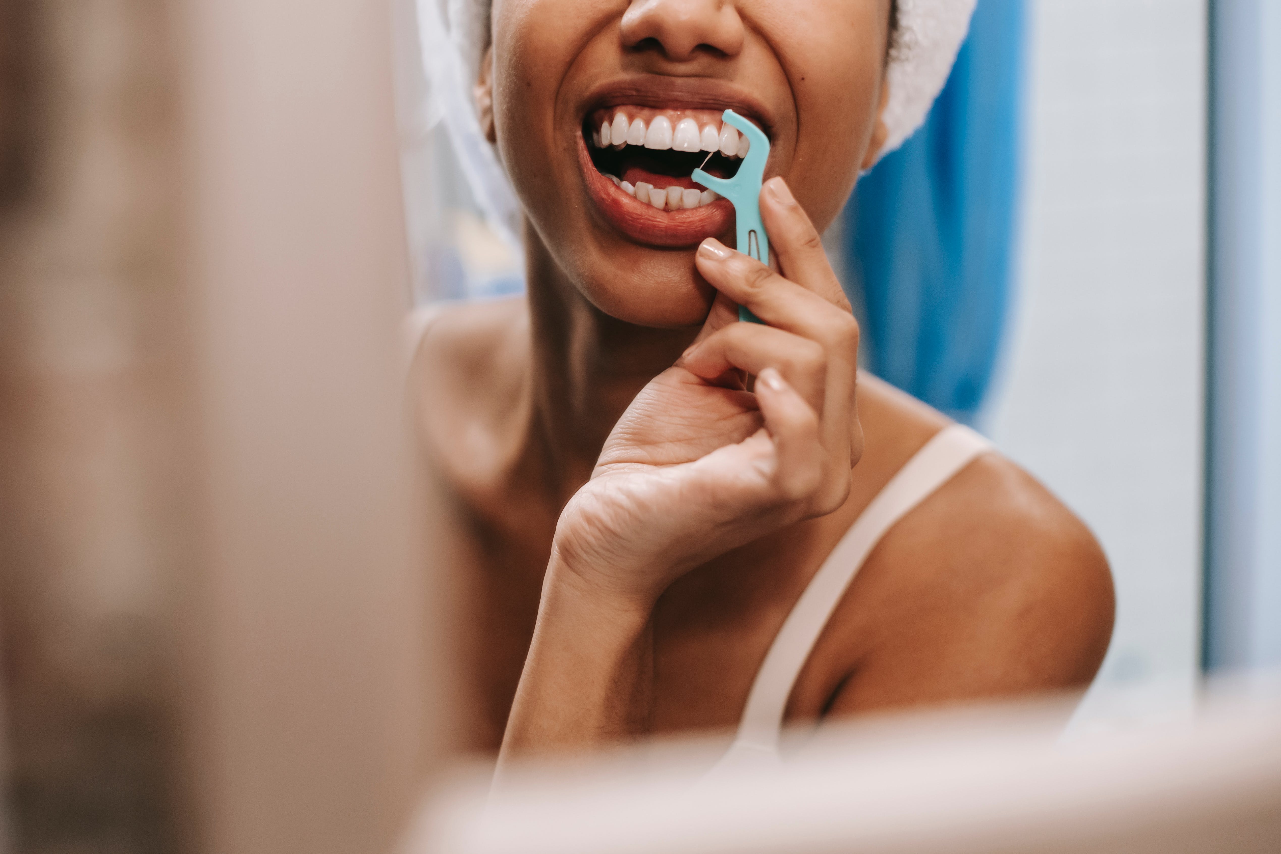 The woman in the image takes care of her dental health by using dental floss