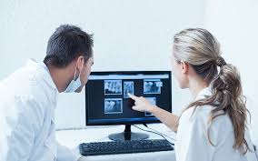 Two dentists examine artificial intelligence radiology detections of their patients