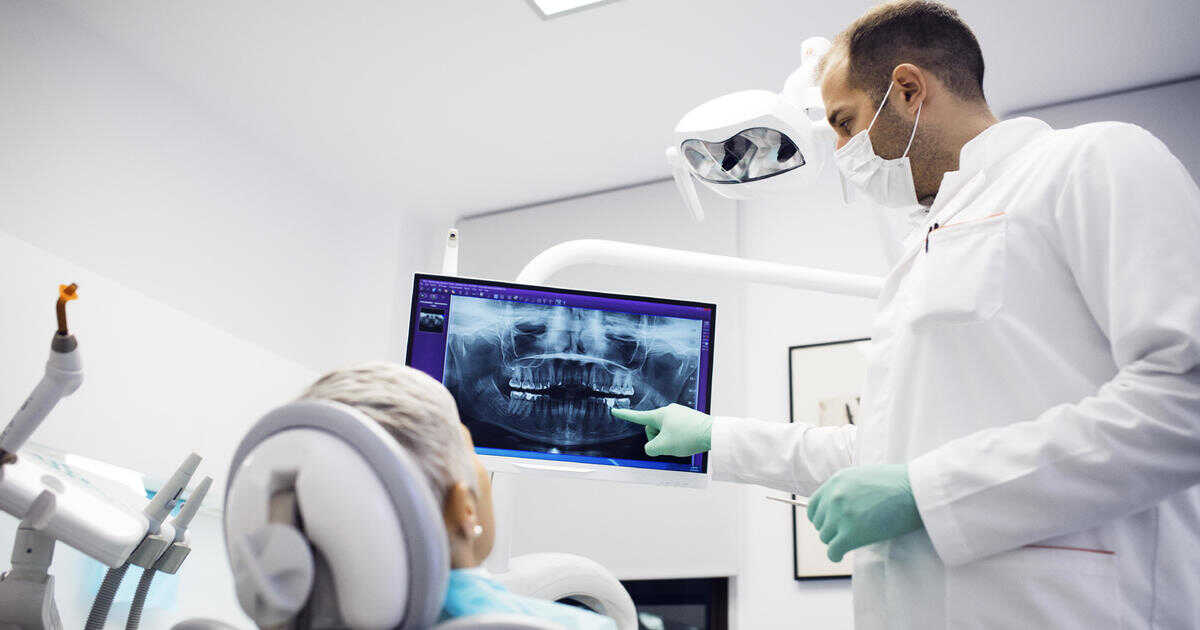 A dentist examining a patient's panoramic dental imaging.