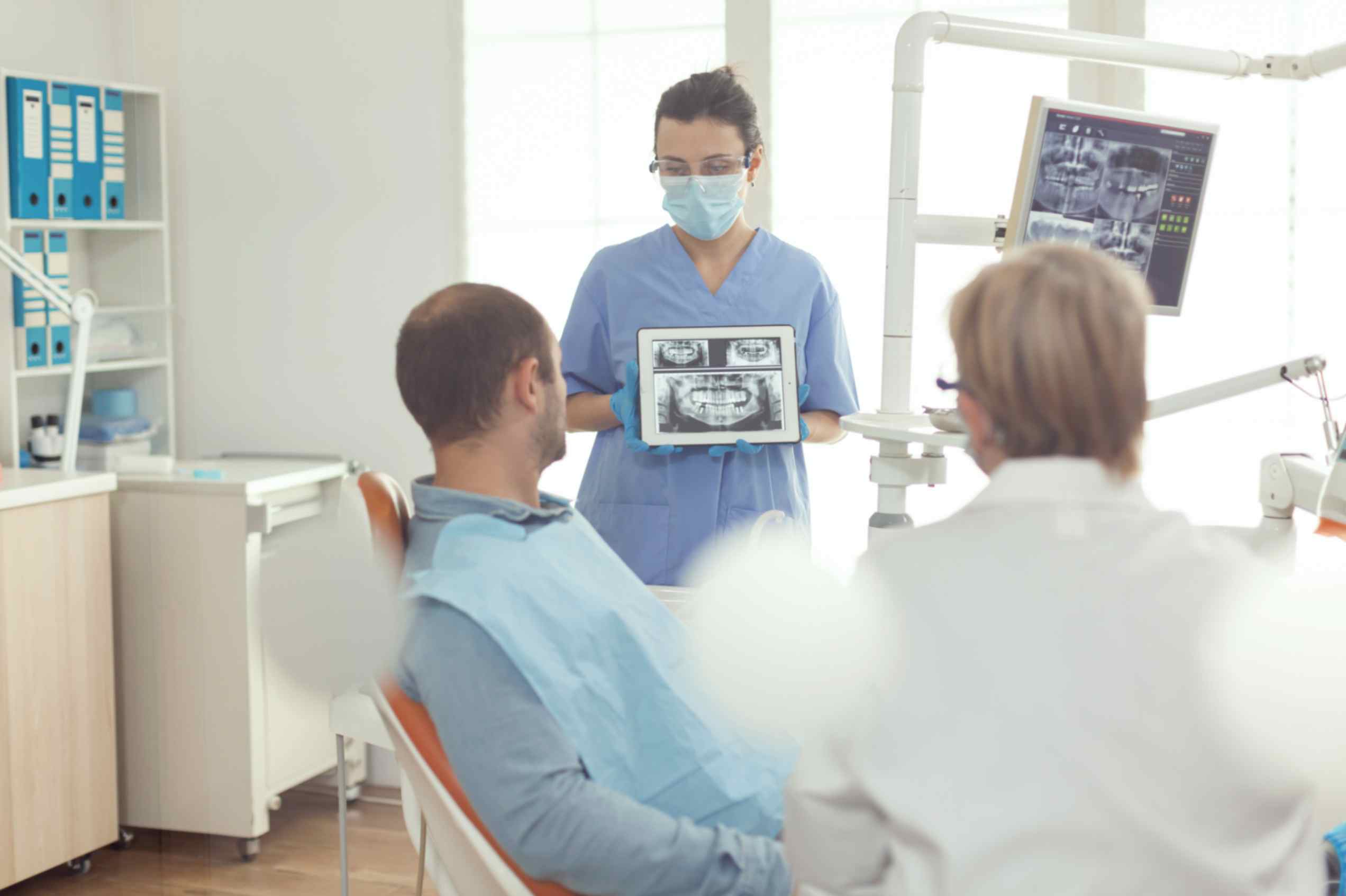 doctor shows dental imaging on tablet to patient